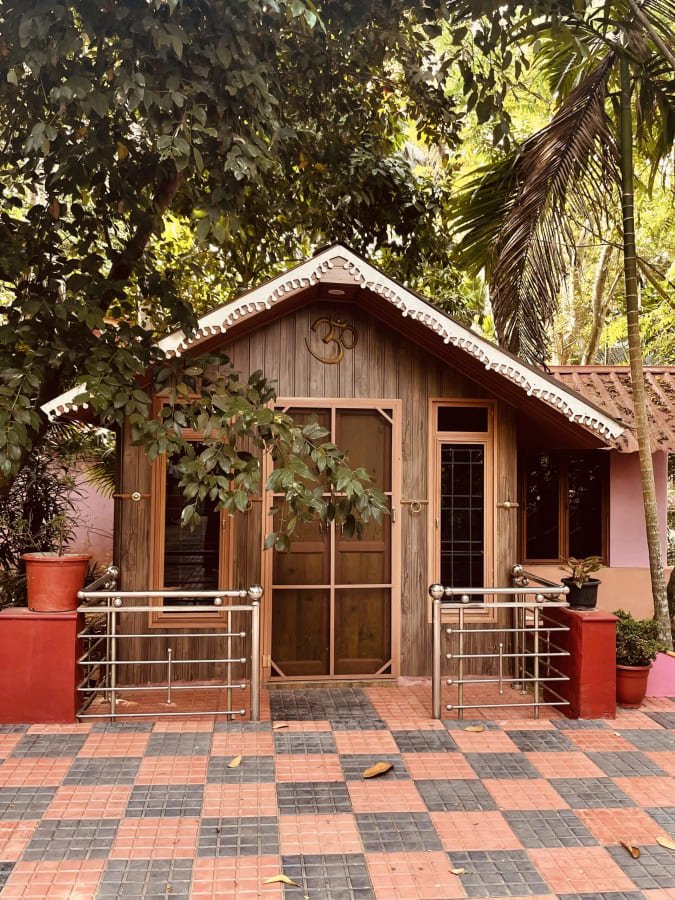 Timber meditation cottage with an Om carved into its gable
