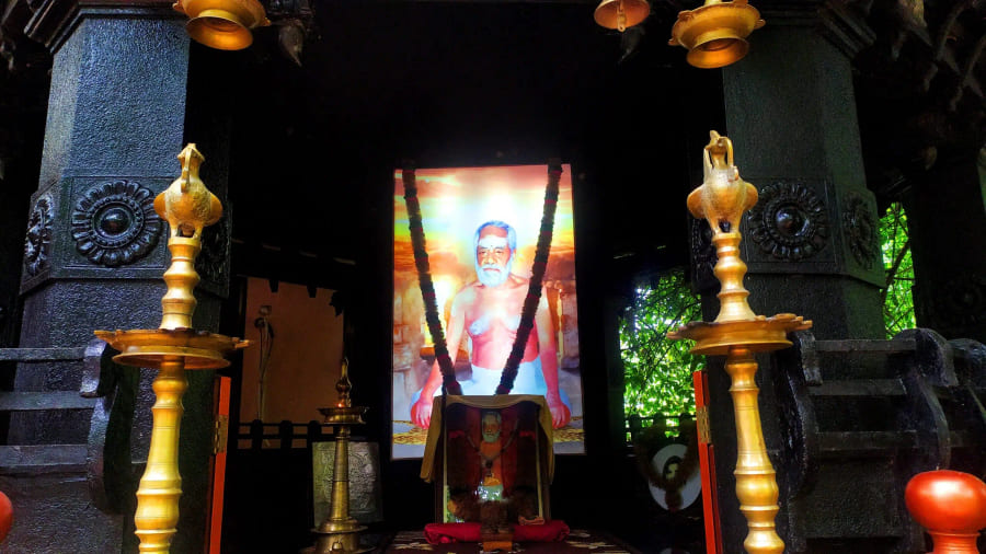 A garlanded portrait enshrined in the temple between two lamps