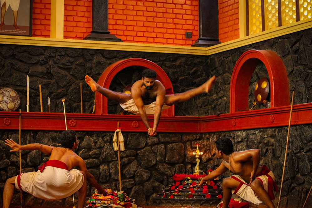 A practitioner holding a mid-air split across the corner of the Kalari