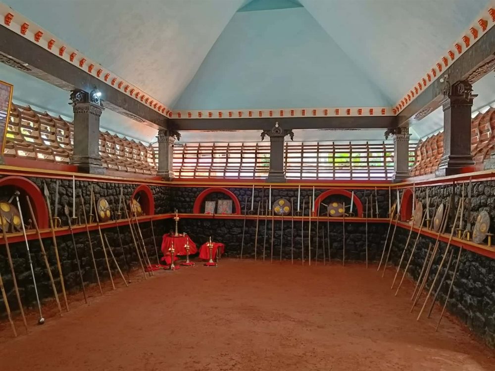 The empty Kalari, its sunken floor ringed by staves and lamps