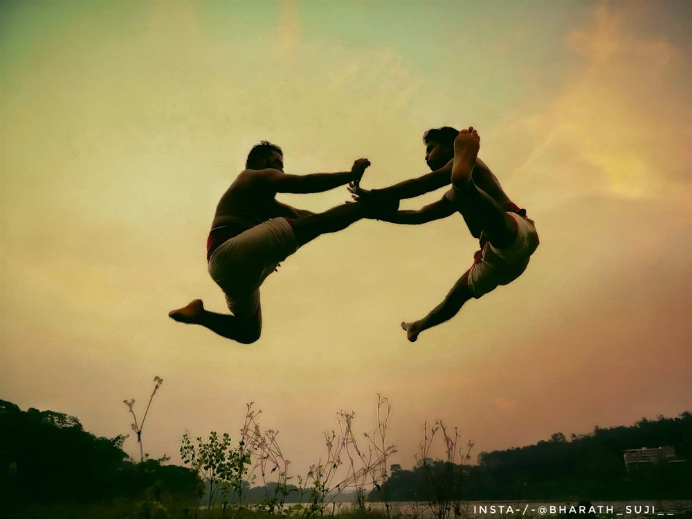 A flying kick met in mid-air, both practitioners in silhouette