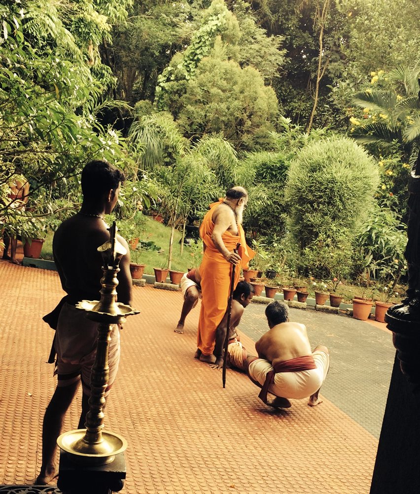 Students receiving Guruji’s blessing beside the lit brass lamp